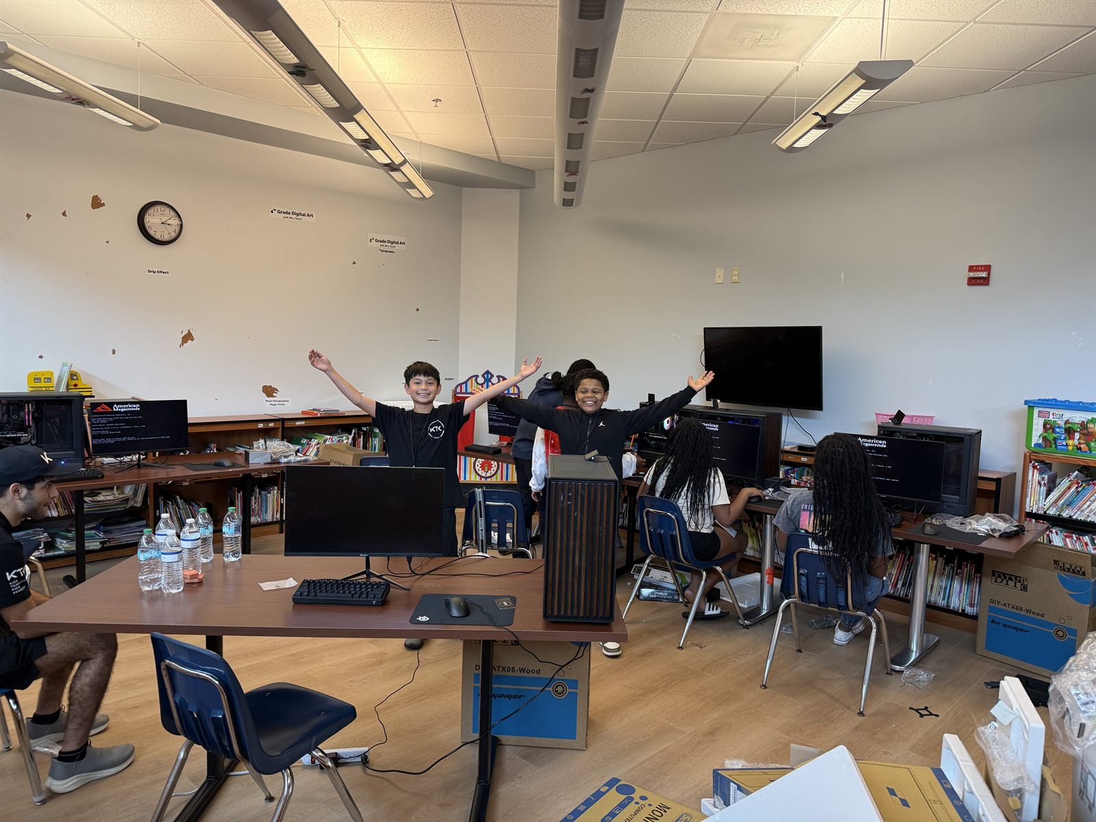 Two campers with their arms in the air behind a finished computer