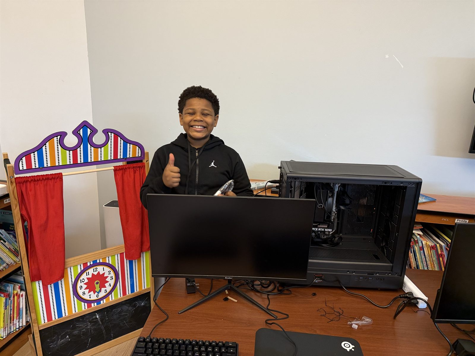 A camper grinning with a thumbs up beside the computer they built