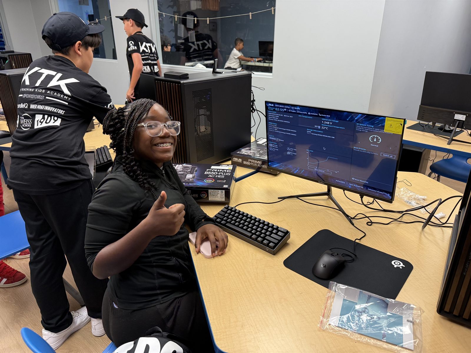 A camper giving a thumbs up at the first boot screen while a teacher works behind her
