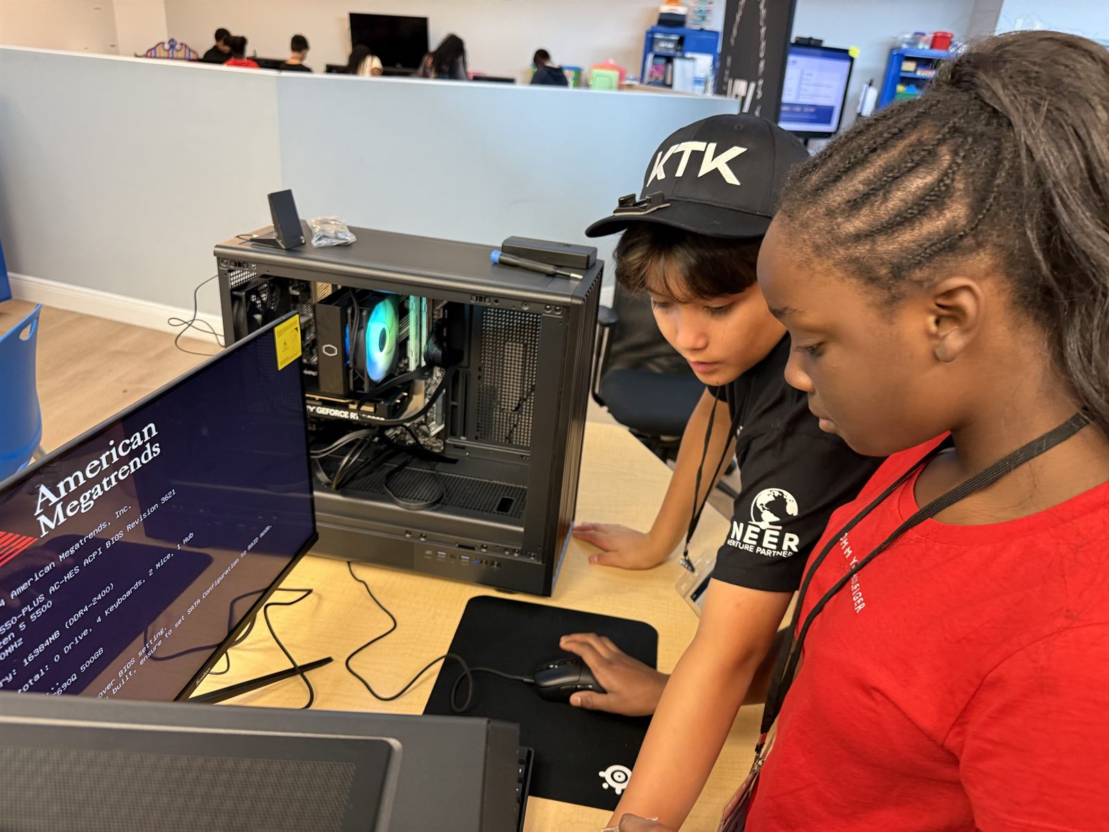Two campers watching the first boot screen on a monitor beside their open case