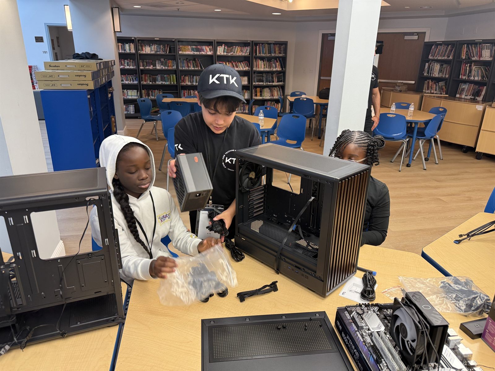 A teacher handing a power supply to a camper at an open case