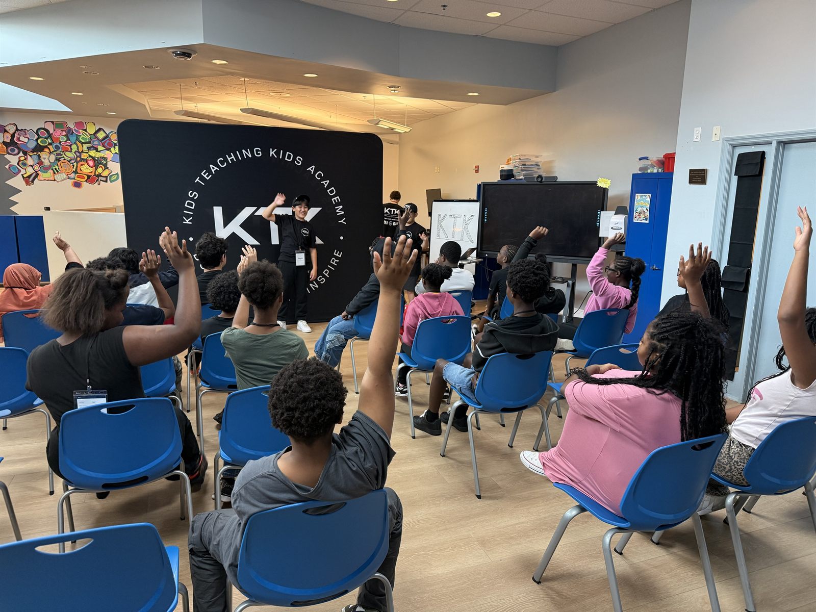 Campers raising their hands to answer a teacher at the KTK backdrop