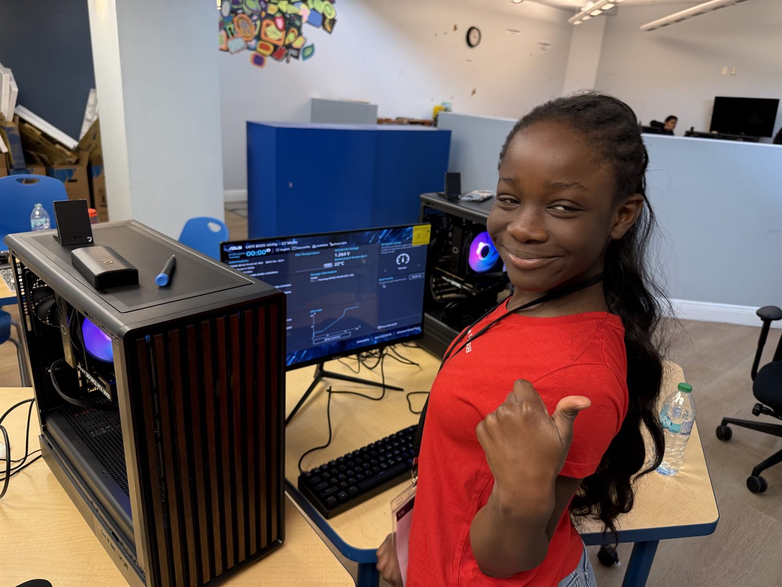 A camper in red giving a thumbs up beside the computer she built