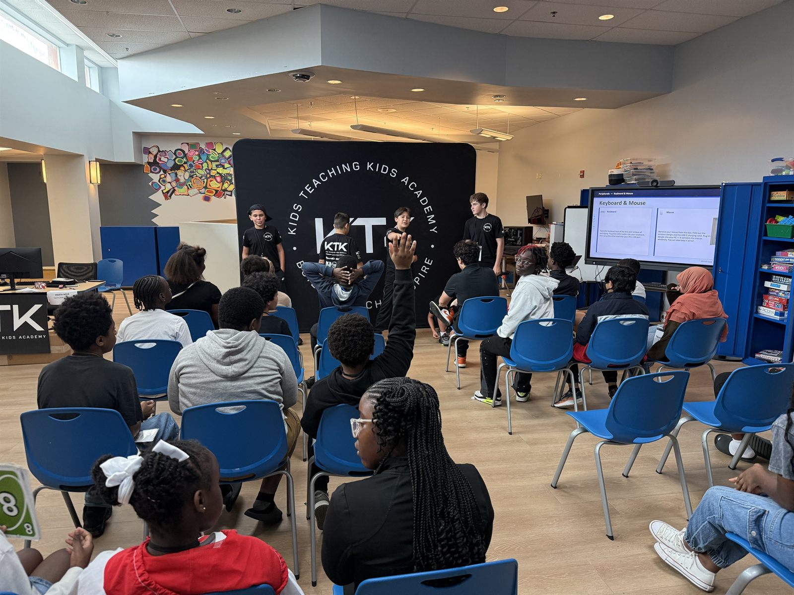 Four teachers at the KTK backdrop presenting to a room of campers