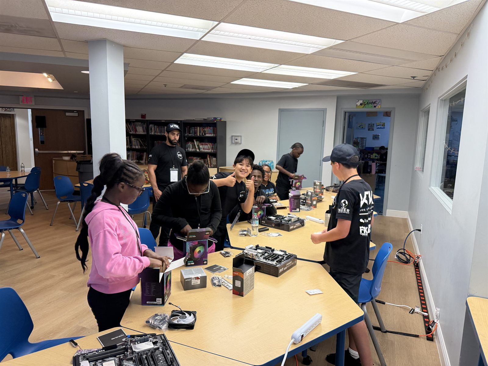 Campers at a table opening the boxes for their parts, a teacher watching